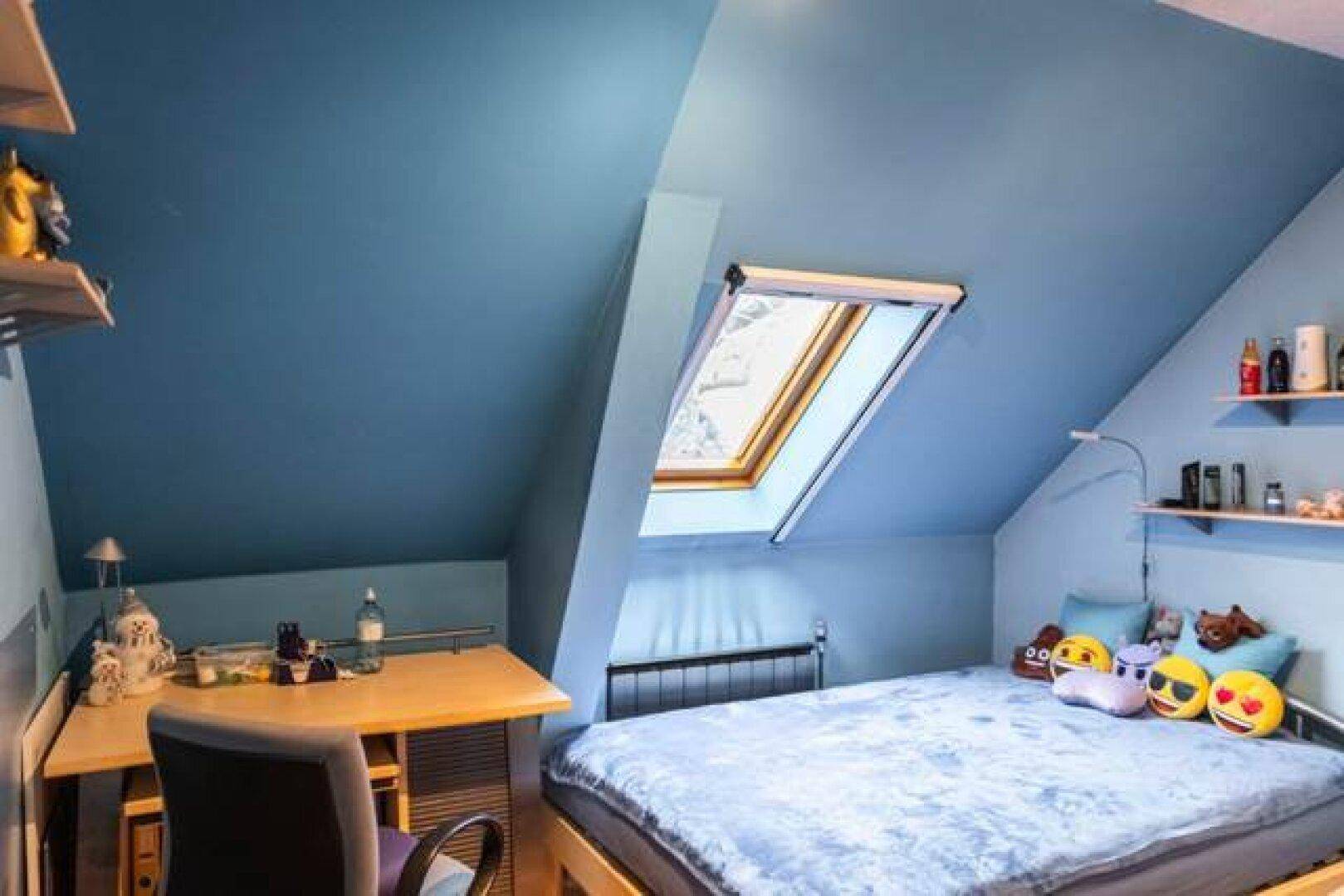 Kinderzimmer oder Arbeitszimmer mit blauen Wänden, Schreibtisch und Dachfenster.