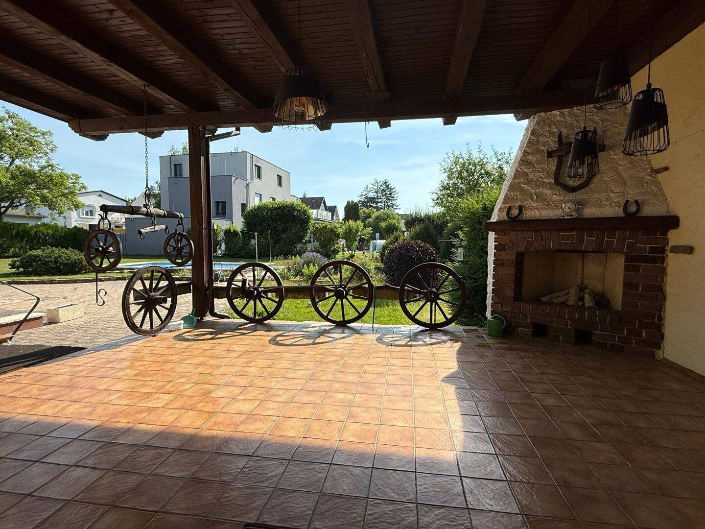 Überdachte Terrasse mit rustikalem Außenkamin und traditioneller Dekoration, ideal für gesellige Abende.