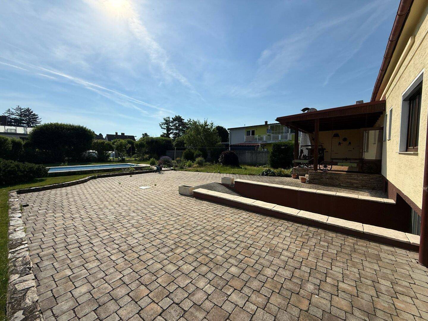 Große gepflasterte Terrasse neben dem Haus, bietet viel Platz für Outdoor-Aktivitäten und Entspannung.