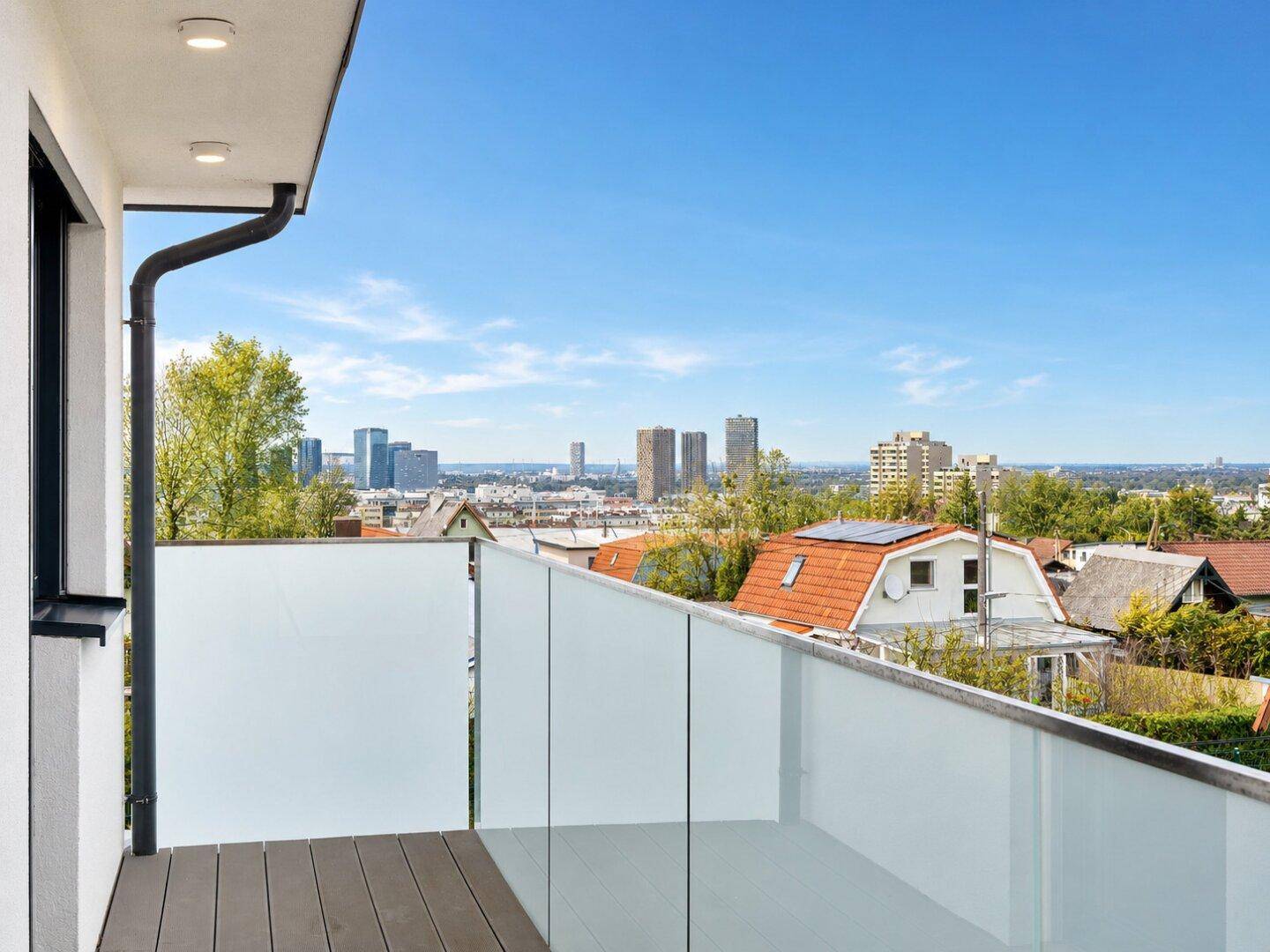 Balkon mit Holzboden und Glasgeländer bietet einen weiten Blick über die Stadt.
