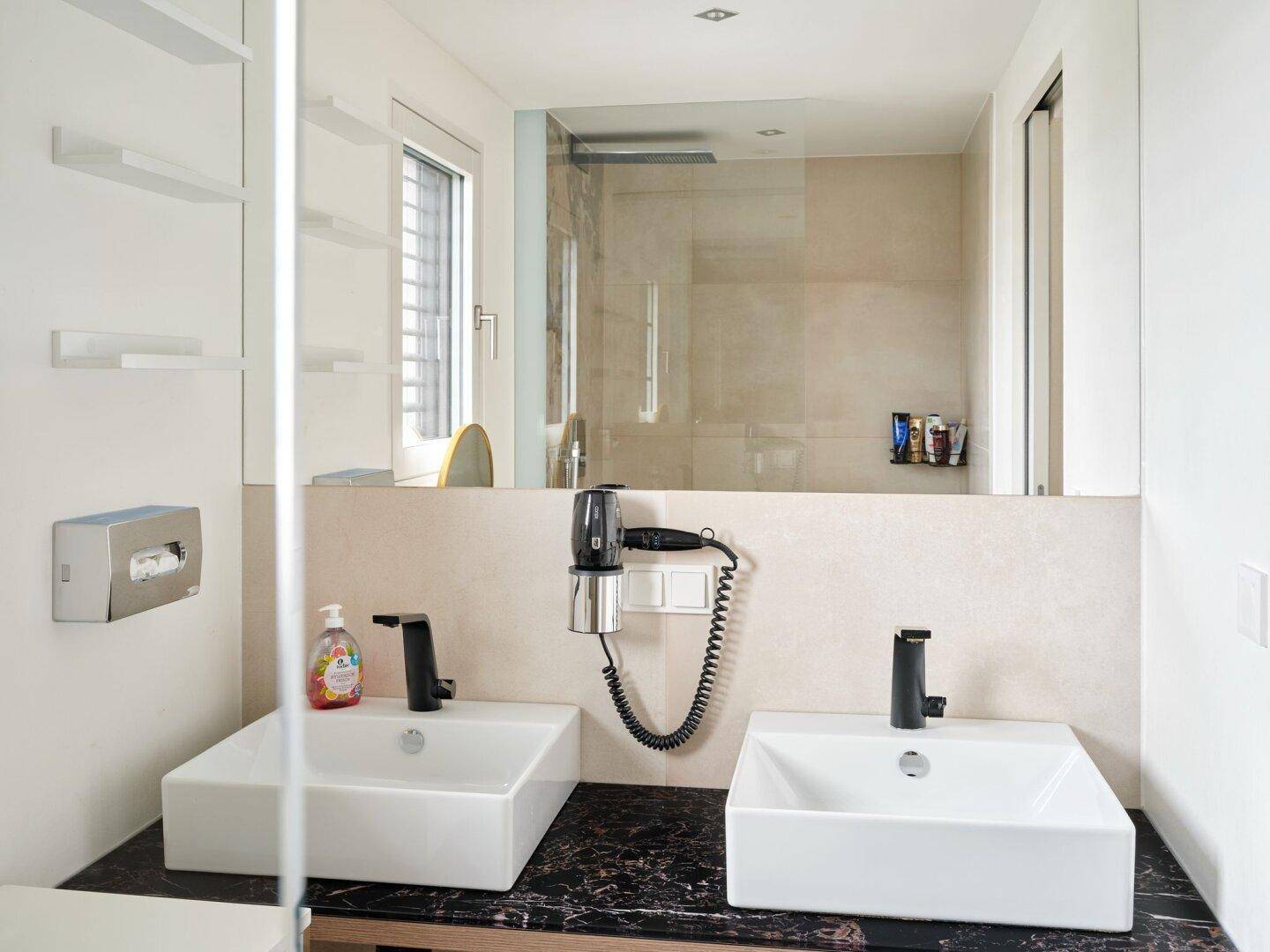 Modernes Badezimmer mit Doppelwaschbecken, großem Spiegel und begehbarer Dusche.