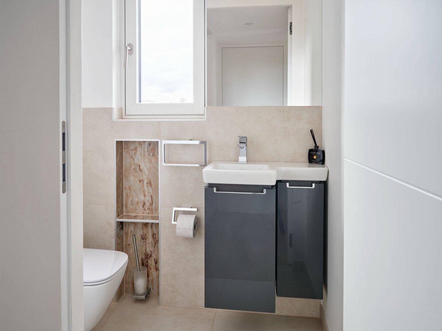 Modernes Gäste-WC mit wandhängender Toilette, kleinem Waschbecken und Fenster.