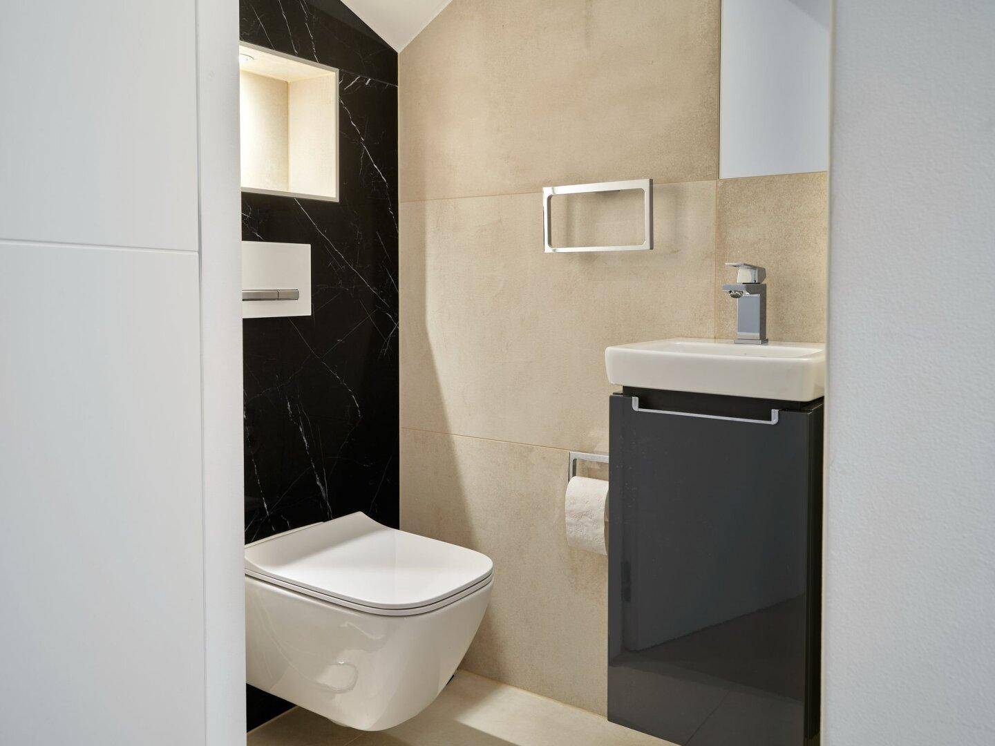 Modernes Gäste-WC mit wandhängender Toilette, kleinem Waschbecken und stilvoller Wandgestaltung.