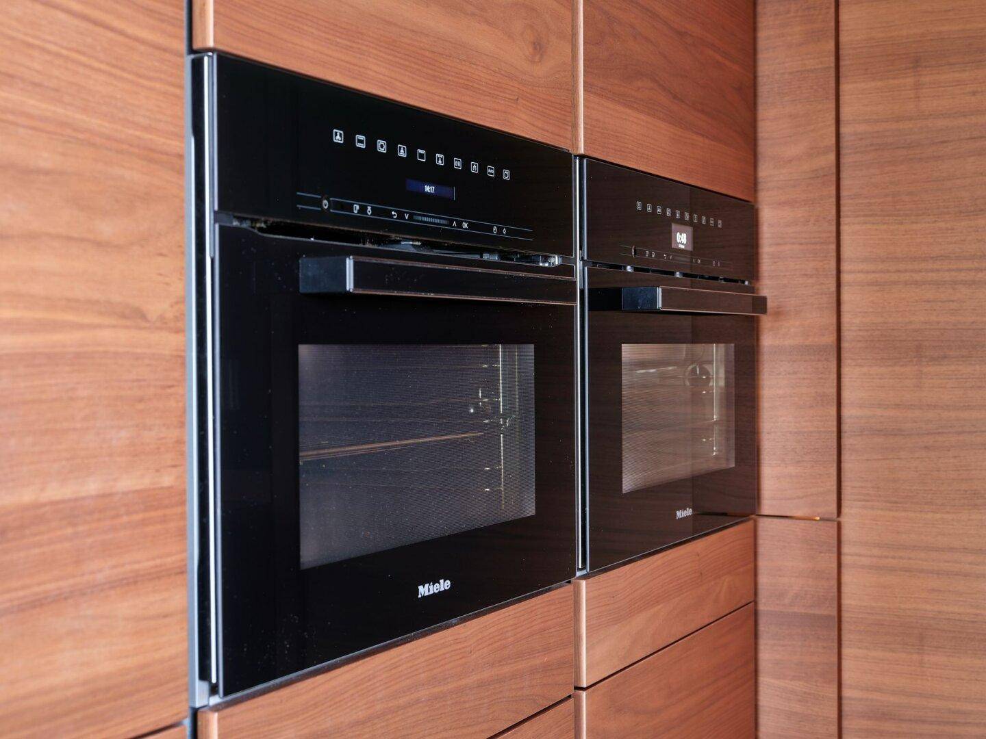 Zwei hochwertige Miele Einbauöfen in einer modernen Holzküche, die Funktionalität und Stil vereinen.