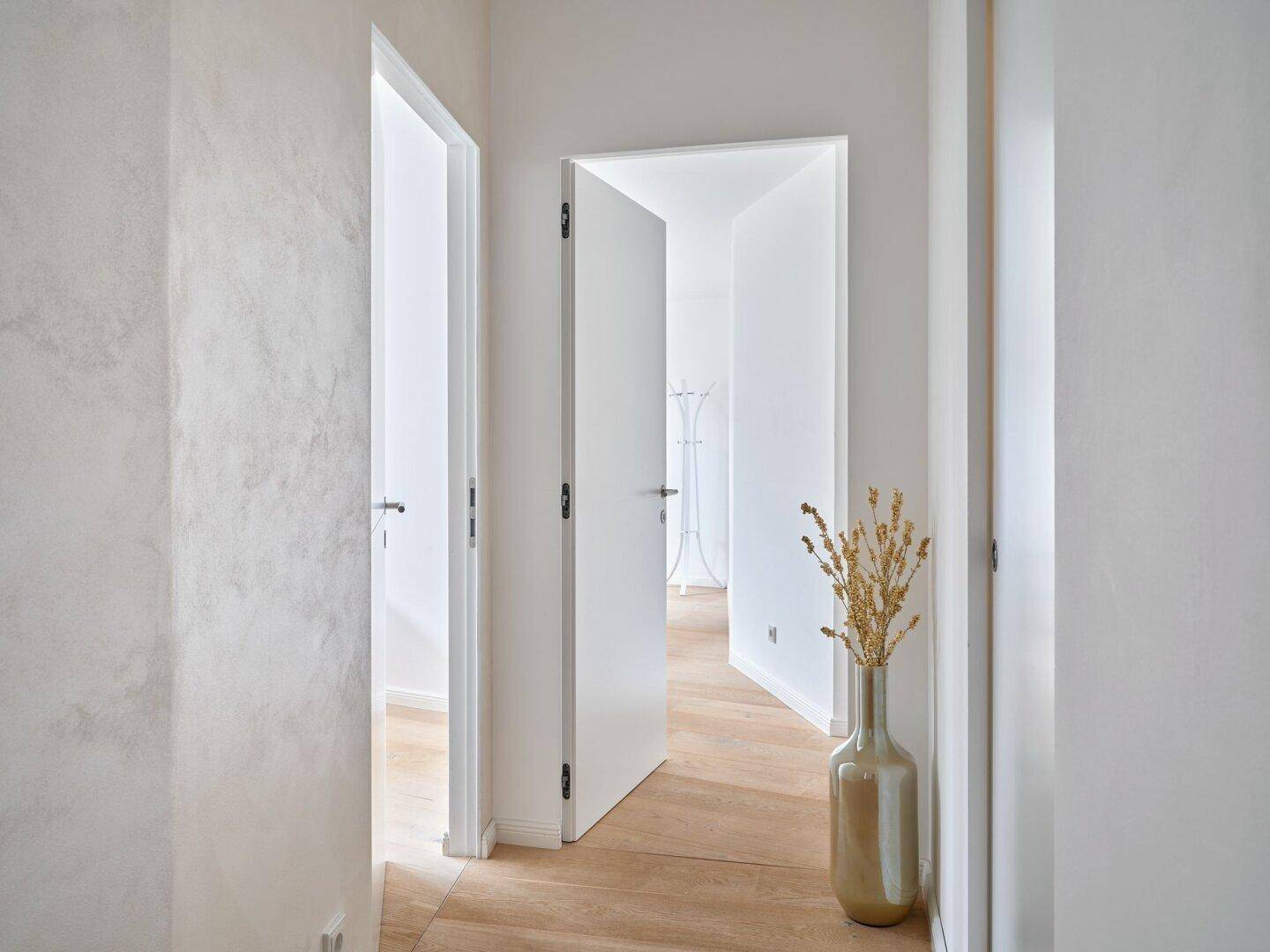 Heller Flur mit Holzboden und mehreren Türen, der zu verschiedenen Räumen des Hauses führt.