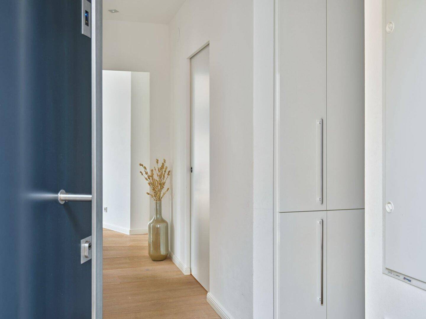 Heller Flur mit Einbauschränken und Holzboden, der einen aufgeräumten und funktionalen Eingangsbereich bietet.