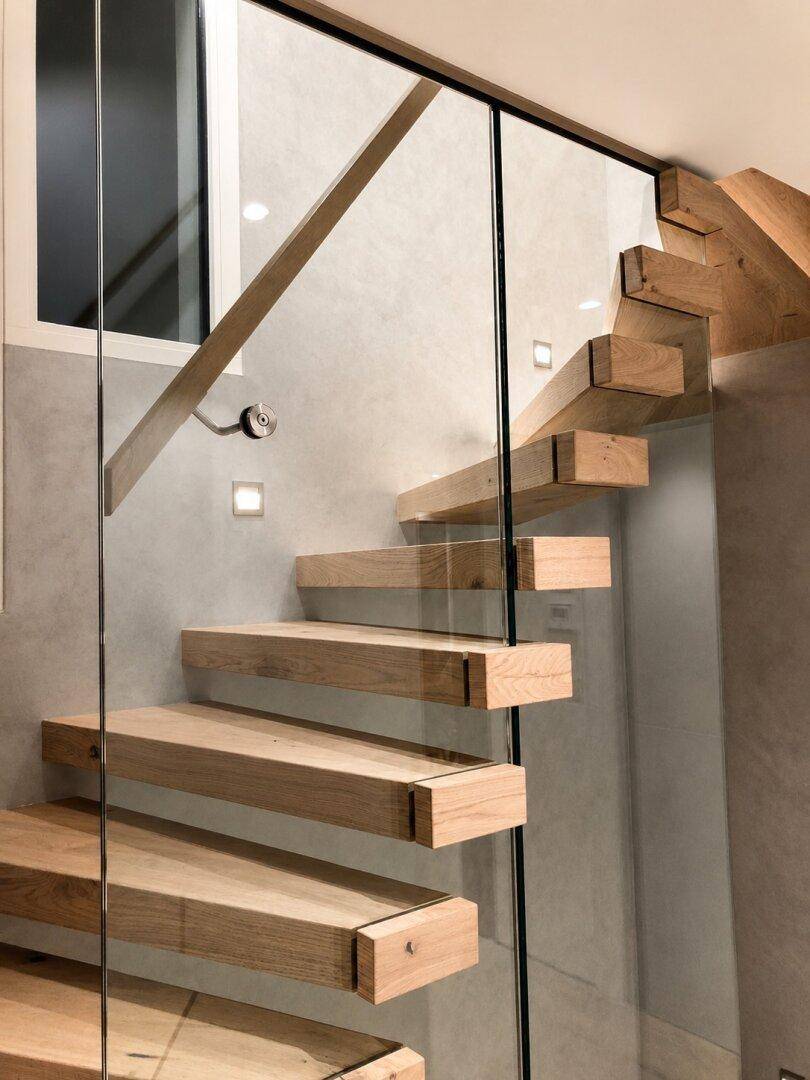 Moderne Treppe mit schwebenden Holzstufen und Glasgeländer, die Eleganz und Leichtigkeit verleiht.