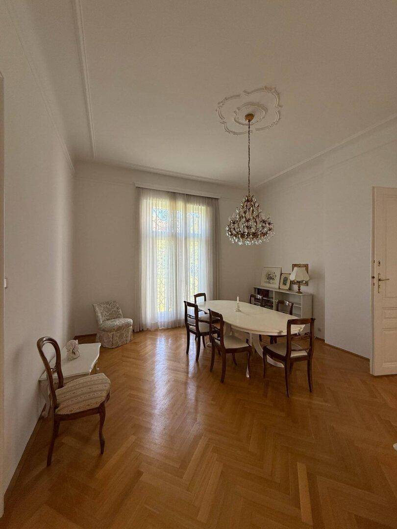Elegantes Esszimmer mit Fischgrätparkett, Stuckdecke und klassischem Esstisch.