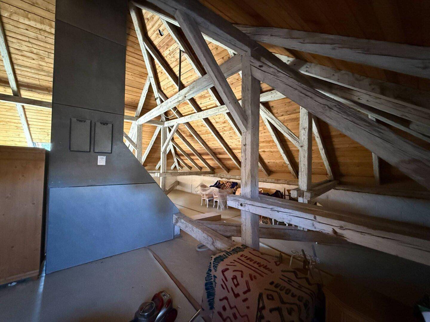 Weiterer Blick in den Dachboden mit freiliegenden Holzbalken und rustikaler Holzdecke.