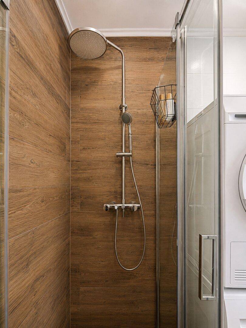 Detaillierte Ansicht der modernen Duschkabine mit Regendusche und Holzoptik-Fliesen.