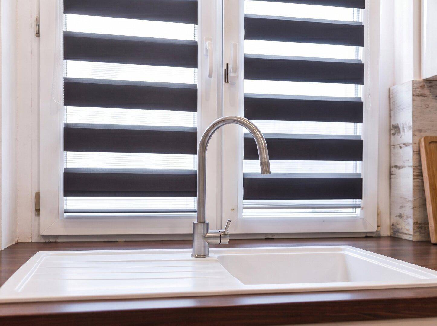 Küchenspüle unter dem Fenster mit modernen Jalousien, bietet viel Tageslicht.