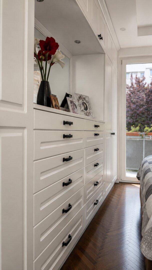 Detailaufnahme der weißen Einbauschränke mit Schubladen im Schlafzimmer.