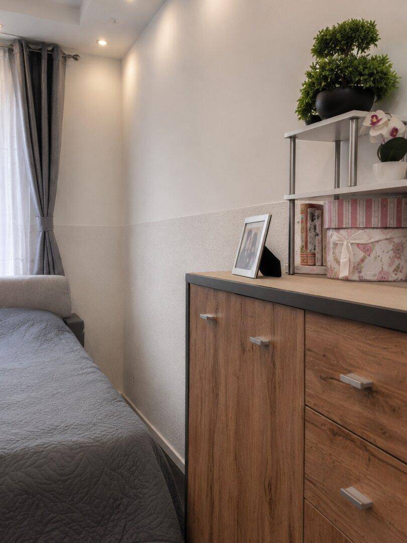 Detailansicht der Kommode und Wandgestaltung im Schlafzimmer mit Fenster.