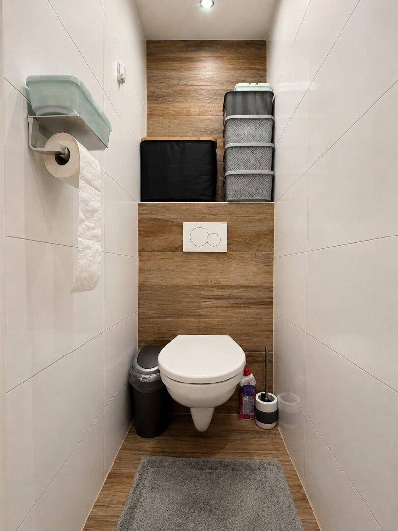 Kleines Gäste-WC mit Wand-WC und modernen Holz- und weißen Fliesen.