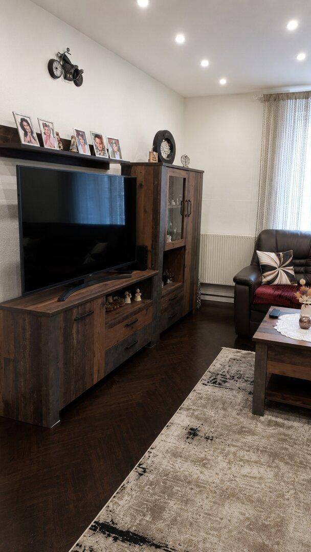Moderner TV-Schrank und Vitrine im Wohnzimmer mit dunklem Holzdekor.