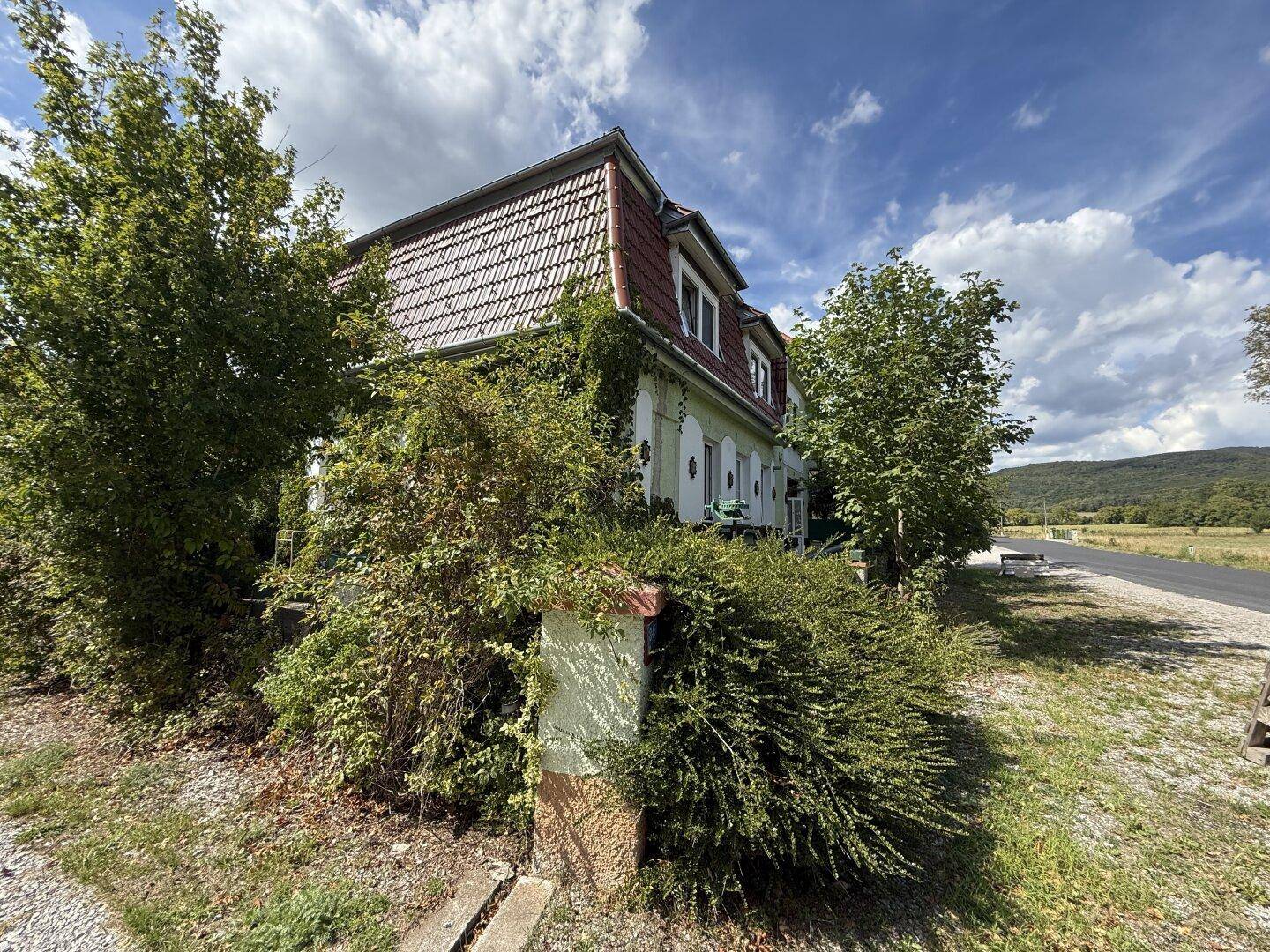 Detailansicht des Hauses mit grüner Fassade, bewachsenen Wänden und Blick auf die Landschaft.