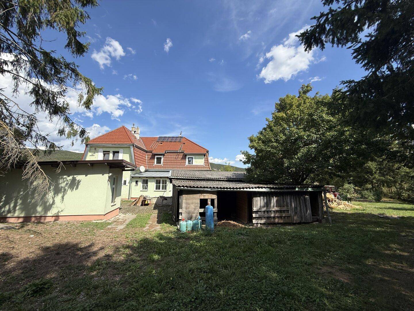 Rückseite des Hauses mit Anbau, Schuppen und Solarpaneelen auf dem Dach.