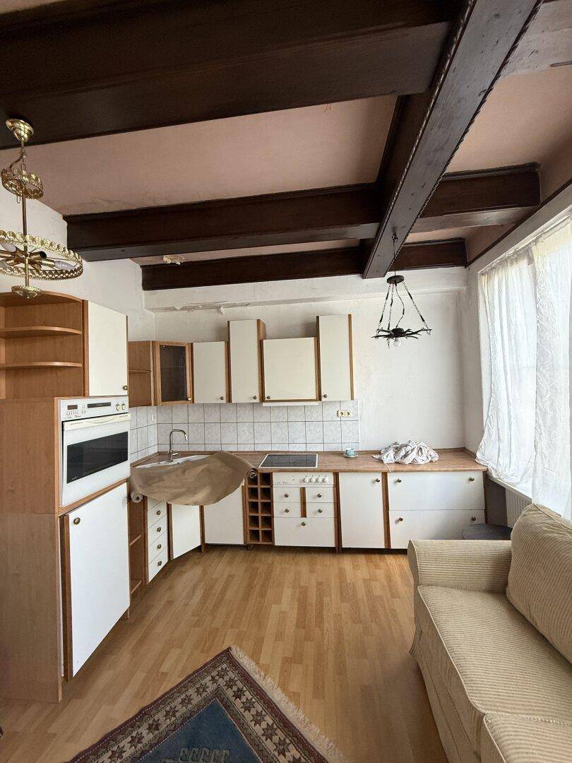 Geräumige Küche mit hellen Schränken, Holzarbeitsplatte und sichtbaren Deckenbalken.