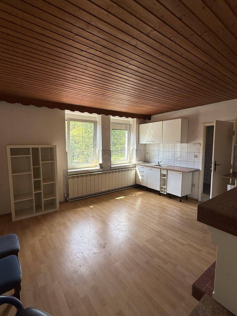 Heller Küchenbereich mit Holzdecke, Laminatboden und Fenster, bietet Potenzial zur Umgestaltung.