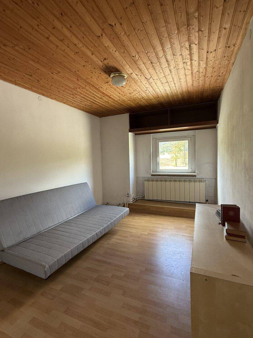 Gemütlicher Raum mit Schlafsofa, Holzdecke und Blick ins Grüne, ideal als Gästezimmer.