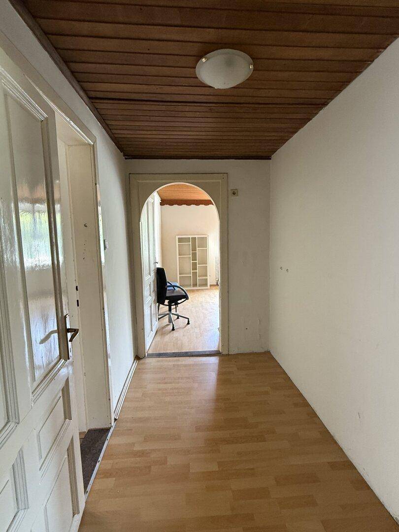 Langer Flur mit Laminatboden und Holzdecke, führt zu weiteren Räumen im Haus.