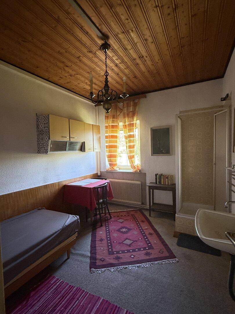 Schlafzimmer mit Teppichboden, Holzdecke, integrierter Dusche und Waschbecken, mit Fenster.