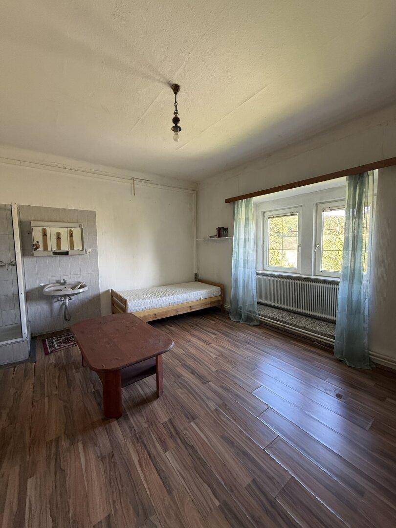 Schlafzimmer mit Laminatboden, Holzdecke, integrierter Dusche und Waschbecken, mit zwei Fenstern.
