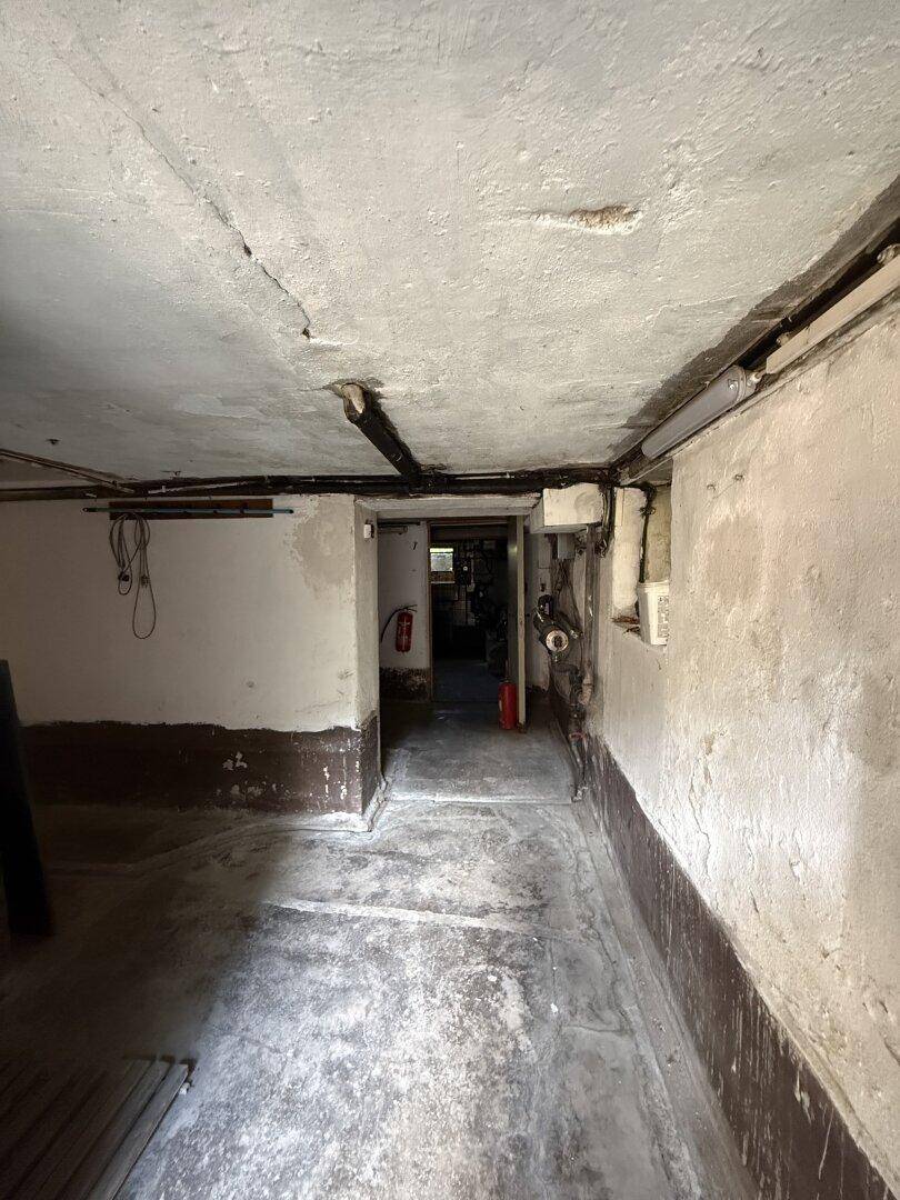 Unausgebauter Kellerraum mit Betonboden und sichtbaren Leitungen, bietet Stauraum.