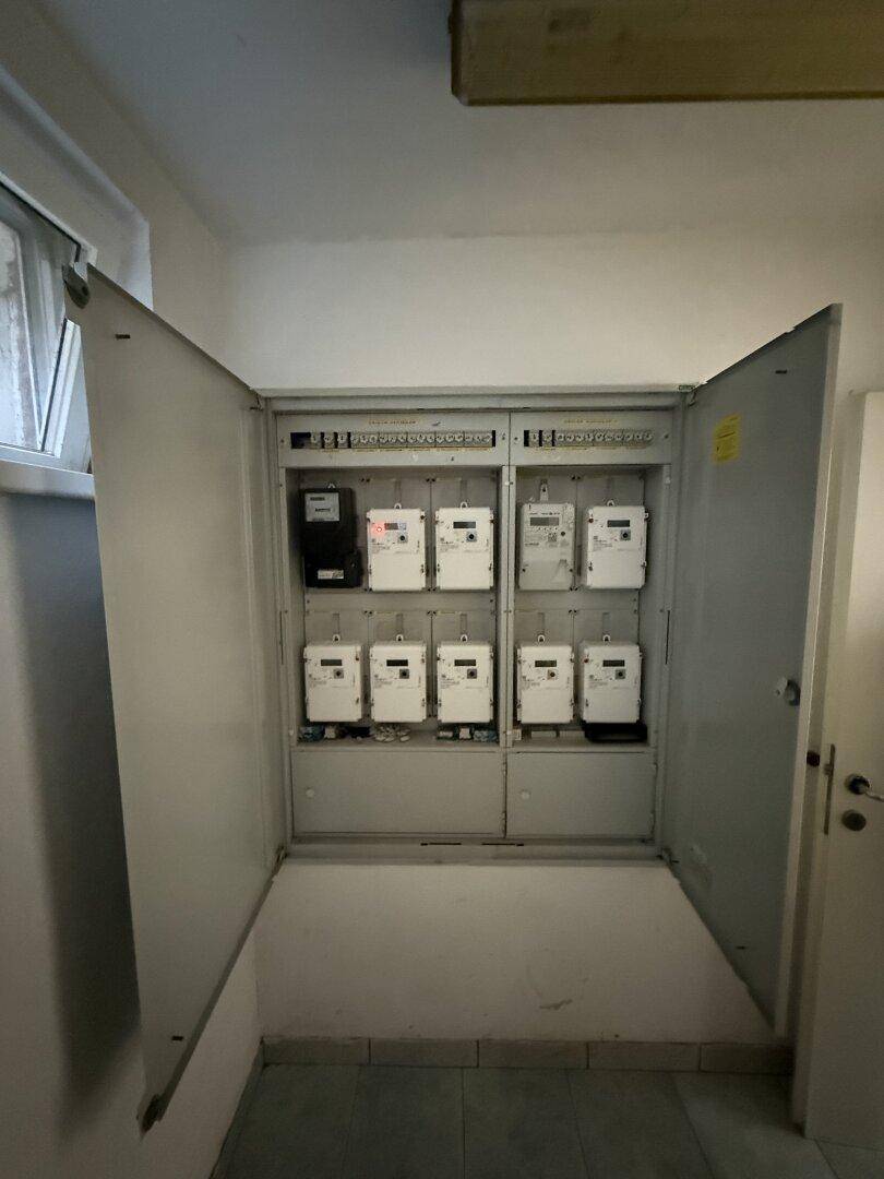Raum mit mehreren Stromzählern und Sicherungskästen, gut beleuchtet durch ein Fenster.