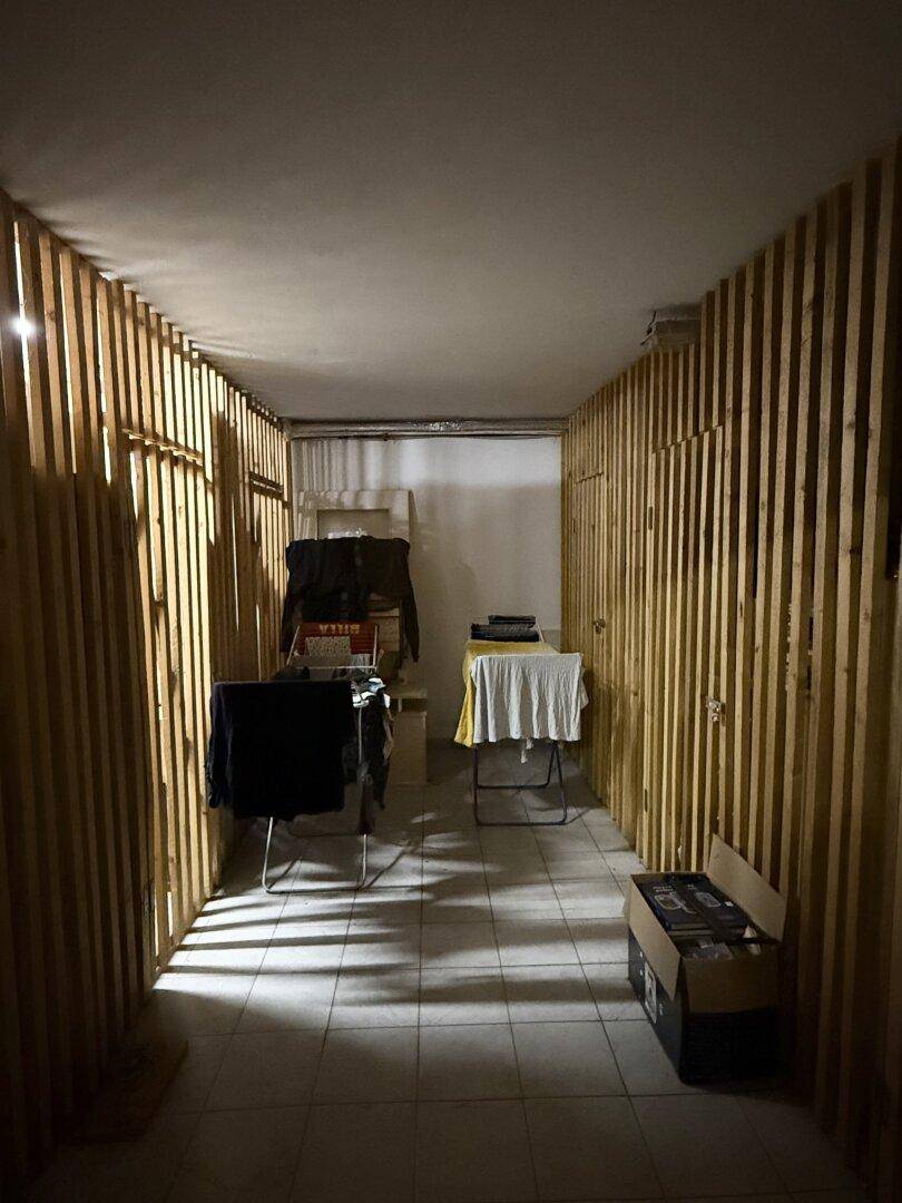 Langer Lagerraum im Keller mit Holzabtrennungen und gefliestem Boden.