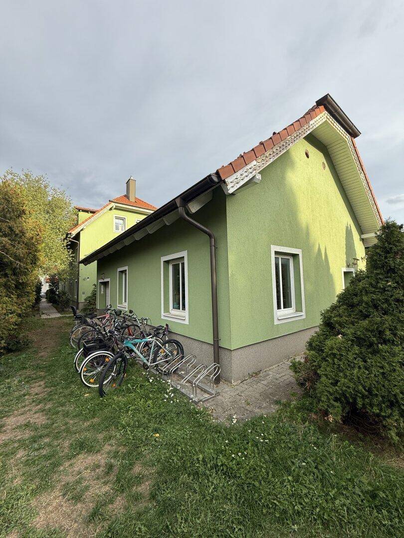 Seitenansicht des Nebengebäudes mit Fahrradständern und grüner Fassade.