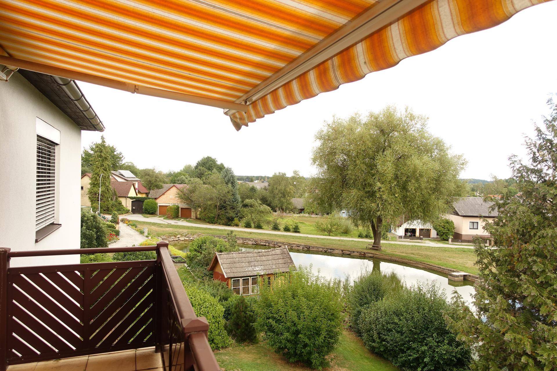 Balkon mit Markise und weitem Blick auf den Teich und die ländliche Umgebung.