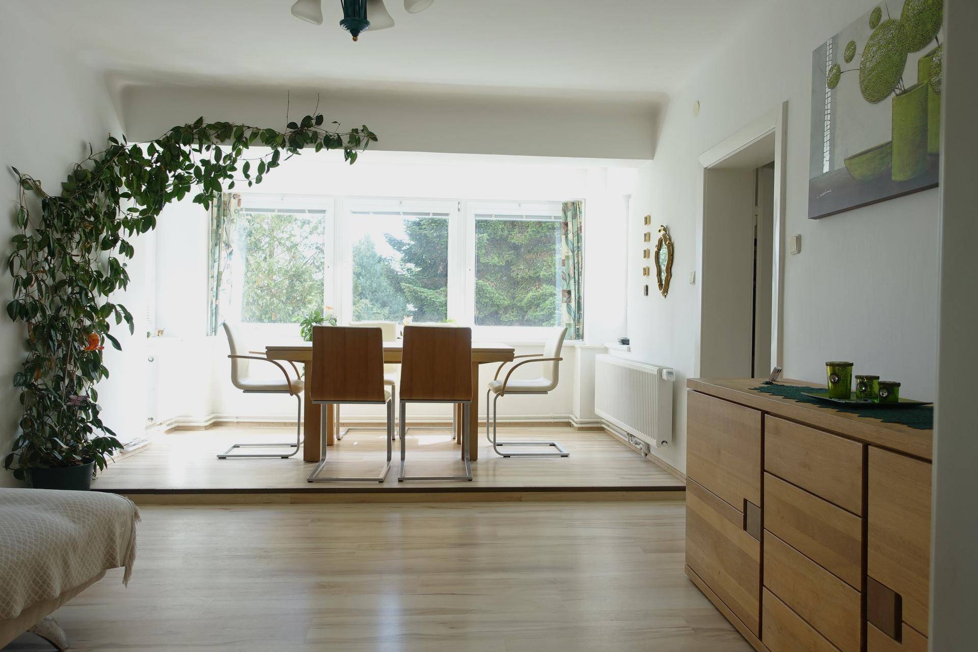 Heller Essbereich mit Holztisch, Stühlen und einer großen Fensterfront mit Blick ins Grüne.