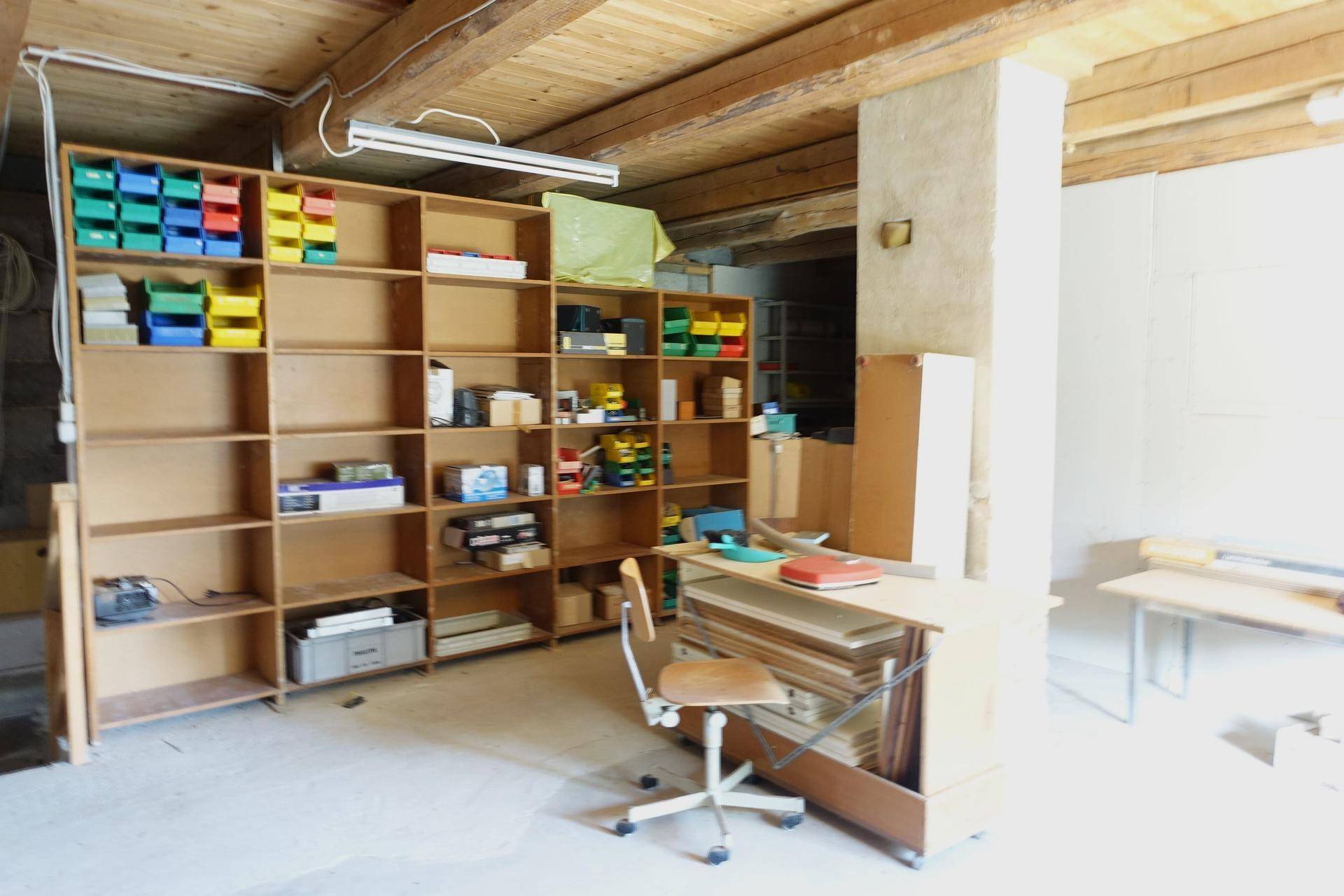 Werkstatt oder Lagerraum mit Holzregalen und sichtbaren Deckenbalken.