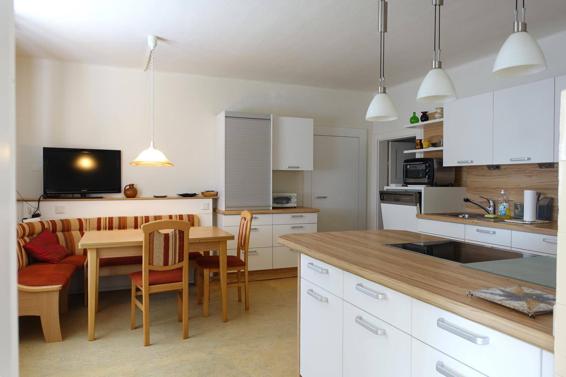 Moderne Küche mit Essbereich, weißen Schränken und Holzarbeitsplatten.