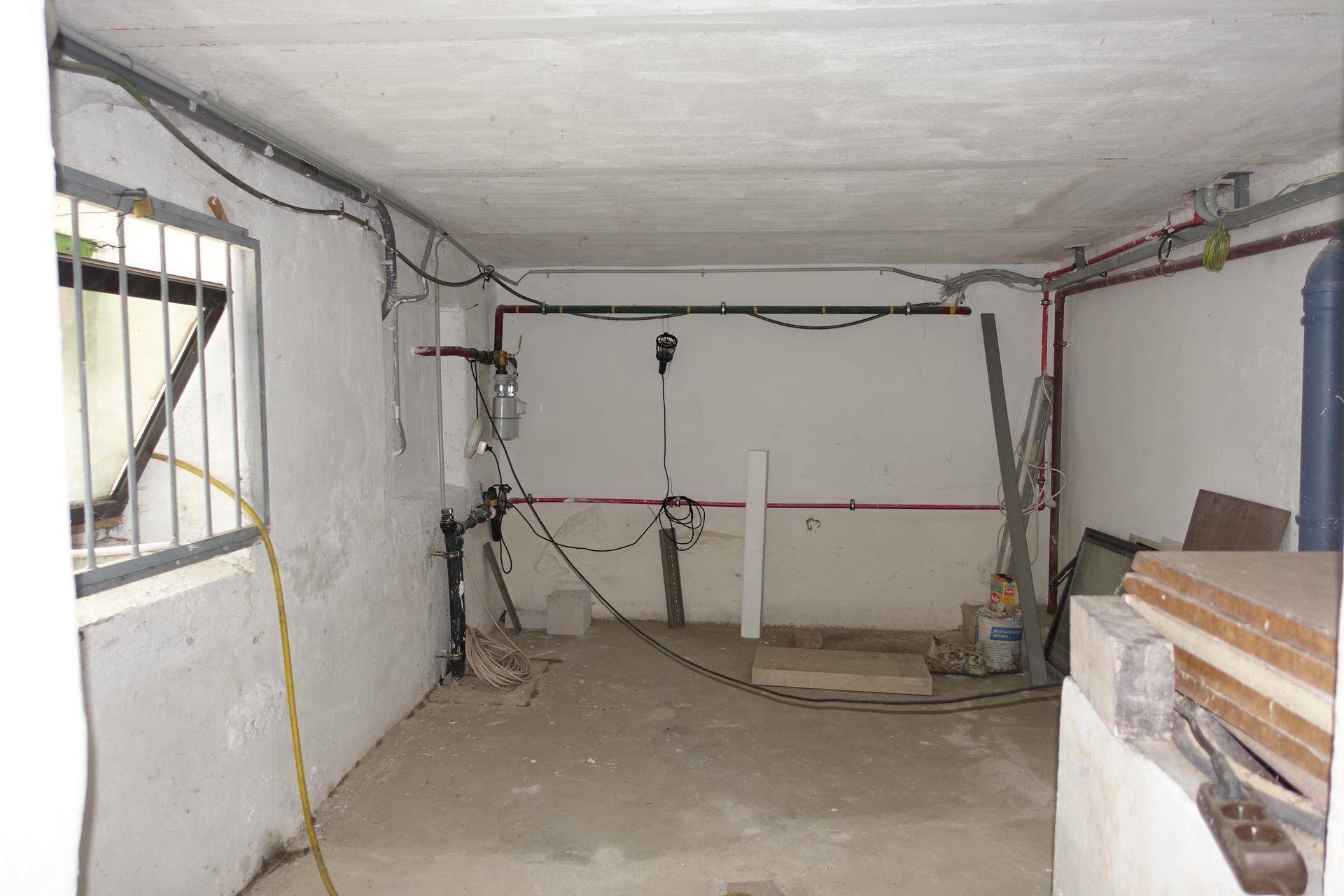 Hauswirtschaftsraum im Keller mit sichtbaren Installationen und Fenster.
