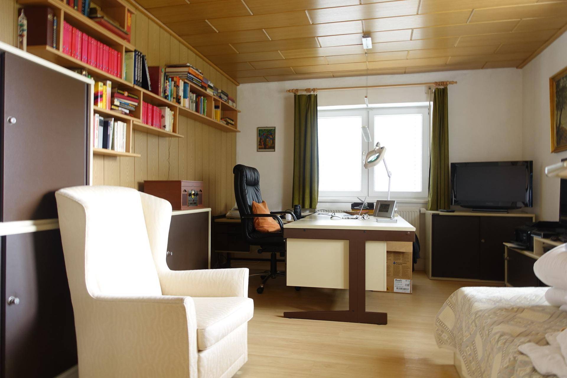 Helles Arbeitszimmer mit Schreibtisch, Bürostuhl und Bücherregalen.