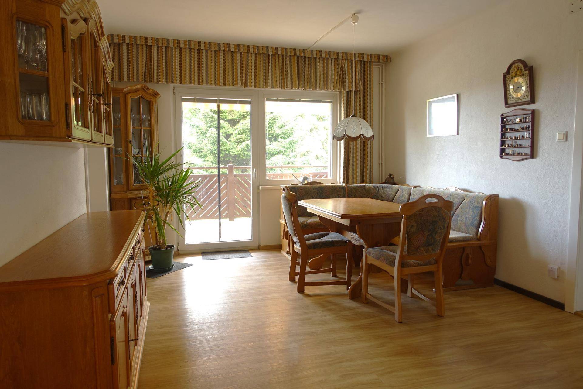 Essbereich mit Eckbank, Holztisch und Zugang zu einem Balkon.