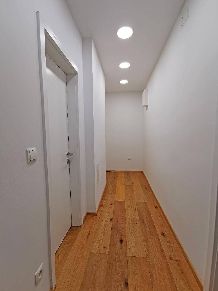 Heller Flur mit Holzboden und modernen Einbaustrahlern in der Decke.