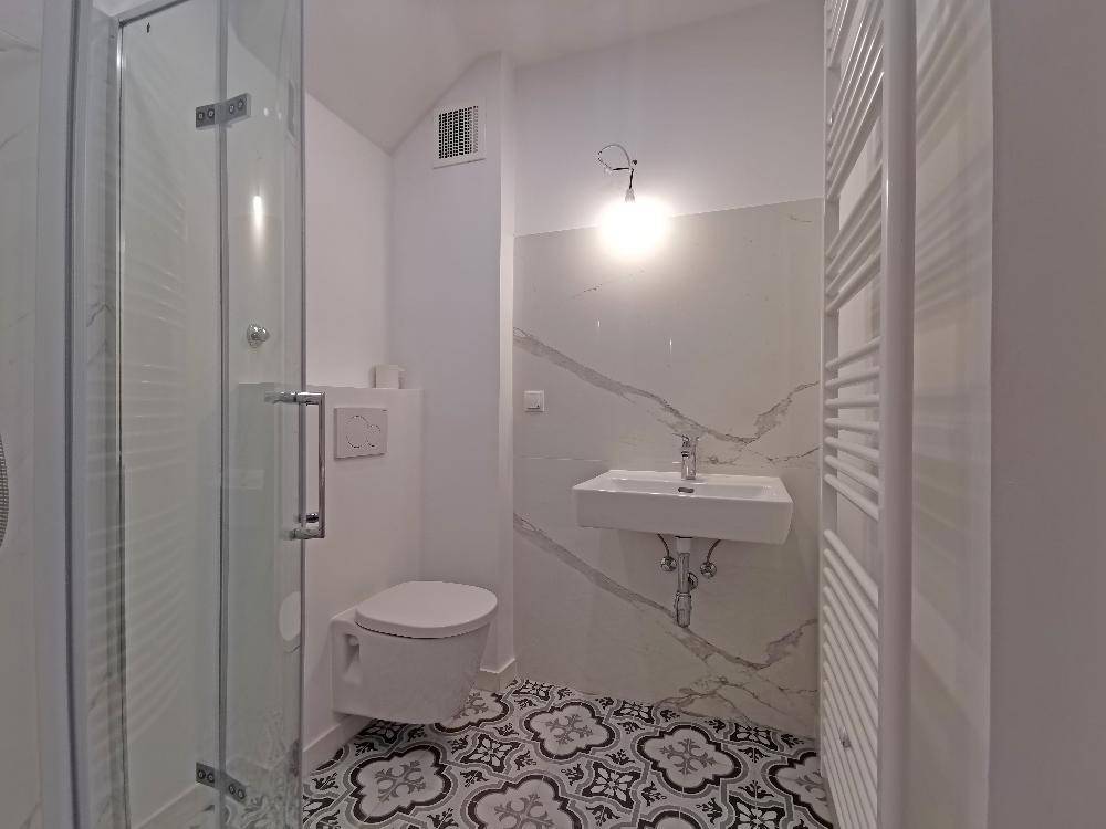 Modernes Badezimmer mit Duschkabine, WC und stilvollen gemusterten Bodenfliesen.