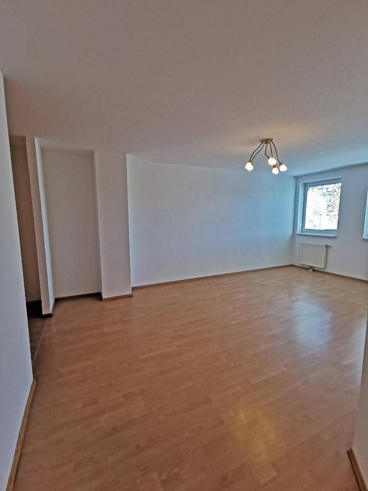 Geräumiges Wohnzimmer mit hellem Parkettboden und weiß gestrichenen Wänden, ideal für neue Einrichtung.