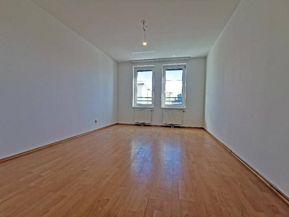 Helles, leeres Zimmer mit Parkettboden und zwei Fenstern, vielseitig nutzbar als Schlaf- oder Arbeitszimmer.