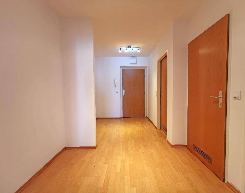 Heller Eingangsbereich mit Parkettboden und Holztüren, führt zu den verschiedenen Räumen der Wohnung.