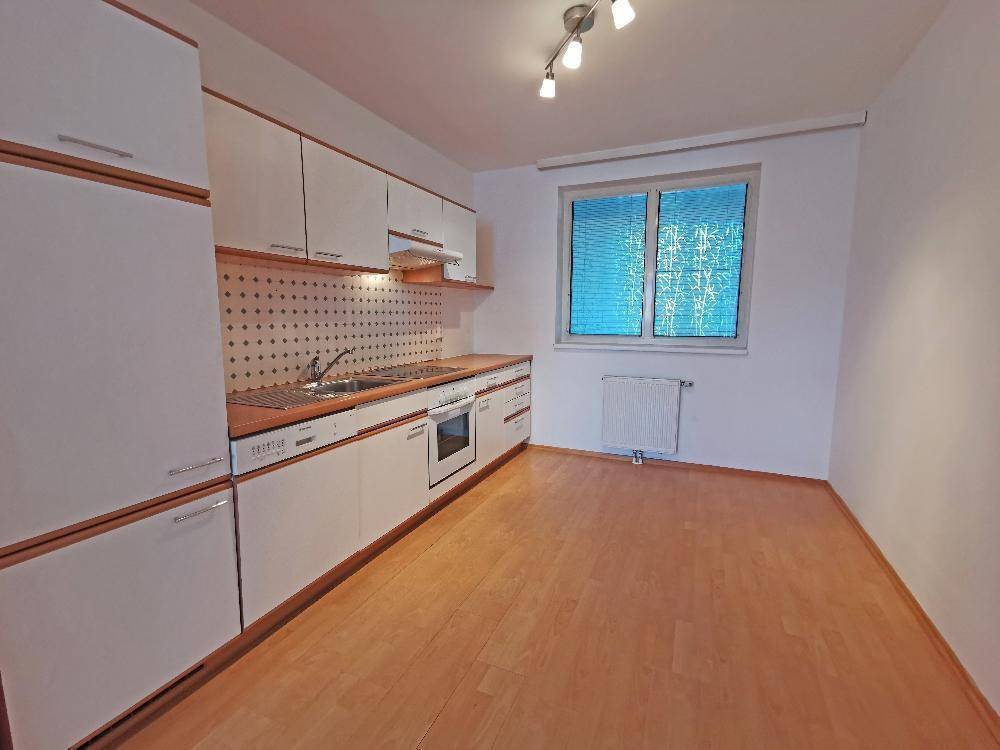 Funktionale Einbauküche mit weißen Schränken, Holztheke und Fenster, bietet Platz für einen Essbereich.