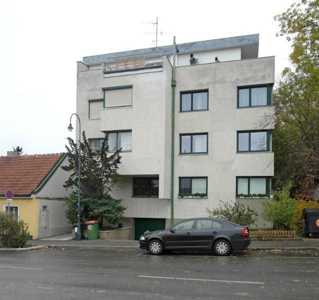 Mehrstöckiges Wohngebäude mit moderner Architektur und Tiefgarageneinfahrt.