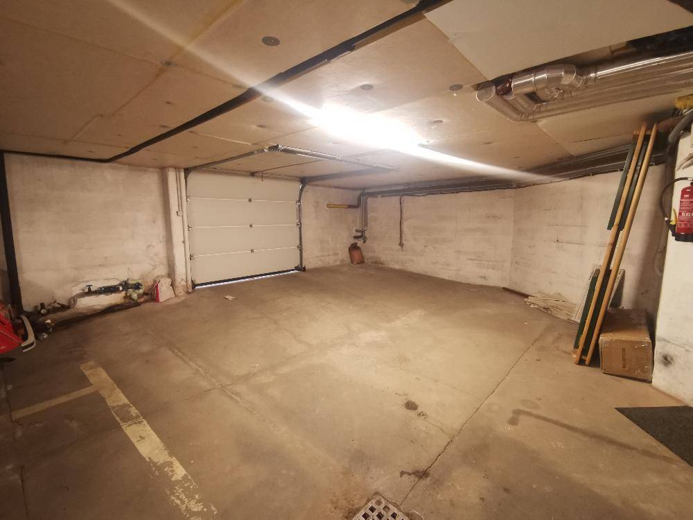 Geräumige Tiefgarage mit Betonboden und geschlossenem Garagentor.