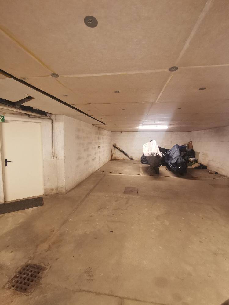 Lange Tiefgarage mit Betonwänden und Lagerfläche für Fahrzeuge.
