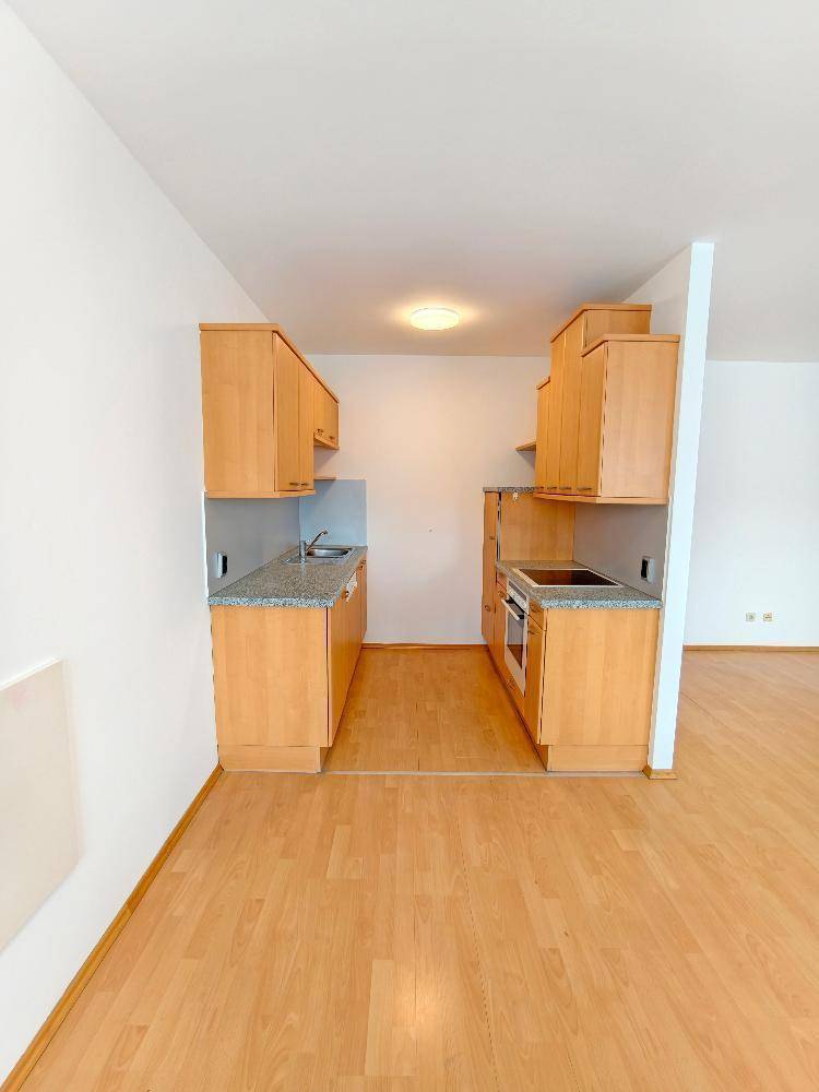 Kompakte Küchenzeile mit Holzschränken, Granitarbeitsplatte und integrierten Geräten für effizientes Kochen.