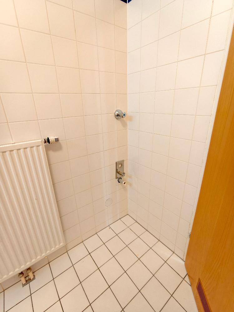 Geflieste Ecke im Badezimmer mit Heizkörper und einfacher Wandgestaltung, praktisch und pflegeleicht.