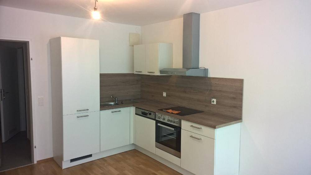 Funktionale Küche mit weißen Schränken, Holzoptik-Arbeitsplatte und integrierten Geräten.